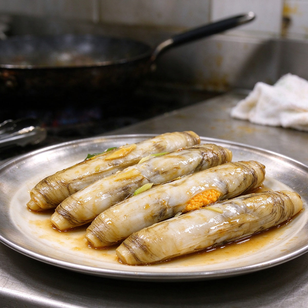Long slender razor clams in the shell showing bright orange roe