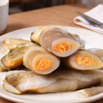 Long slender razor clams in the shell showing bright orange roe