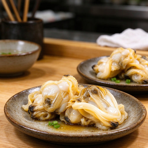 Plump shucked clam meat with pale golden mantle, rinsed in a colander